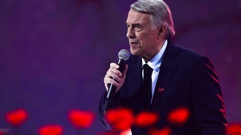 Salvatore Adamo, seine Lieder und Chansons: Der belgische Sänger singt in einer Fernsehshow im April 2019 vor rotblühenden Blumen.