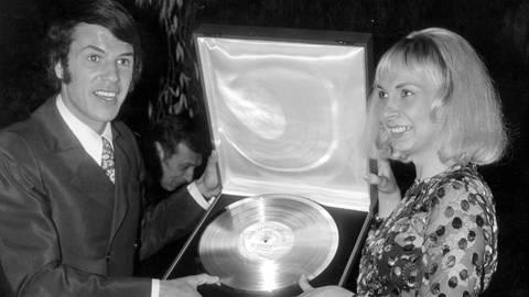 Salvatore Adamo, seine Lieder und Chansons: Der belgische Sänger posiert mit seiner damaligen Frau Nicole zusammen mit einer Goldenen Schallplatte, beide freuen sich (Oktober 1969).