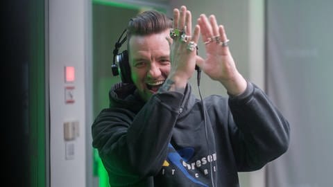 Ein Mann steht mit Kopfhörern vor einem Mikrofon und klatscht freudig vor dem Gesicht in die Hände - Ben Zucker stellt sein neues Album "Heute nicht!" vor (Foto: SWR)