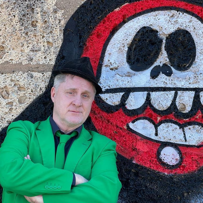 Bernd Kohlhepp steht vor einer Wand mit einem Graffiti