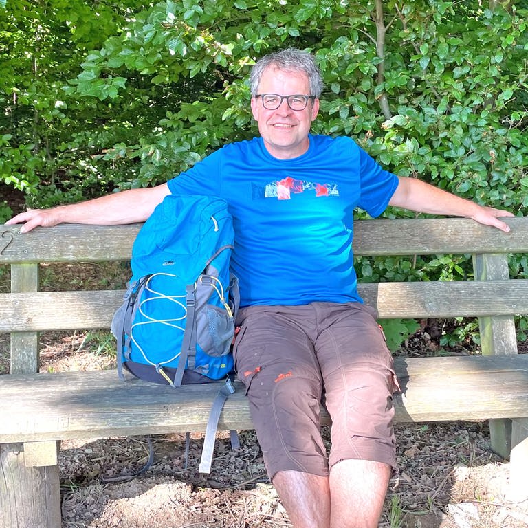 SWR4 Moderator Holger Bentzien sitzt bei einer Rast auf Wanderung, den Rucksack neben sich