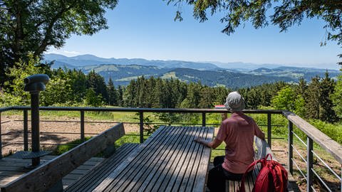 Eine Frau sitzt am Tisch und schaut in die Ferne auf dem Rundwanderweg im Allgäu durch den Eistobel zur Riedholzer Kugel. (Foto: Herbert Neidhardt | tt-bilder)