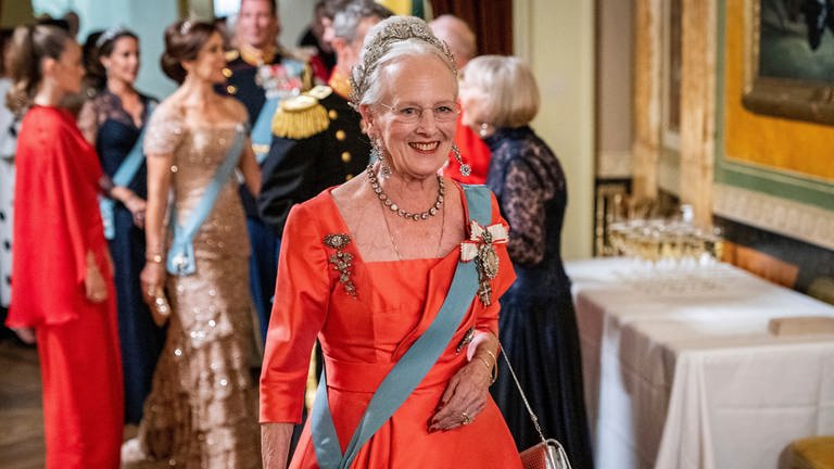 Königin Margrethe II. von Dänemark – ihr bewegtes Leben: Die Regentin zeigt sich lächelnd mit rotem Kleid im Danish Royal Theatre. (Foto: dpa Bildfunk, Picture Alliance)