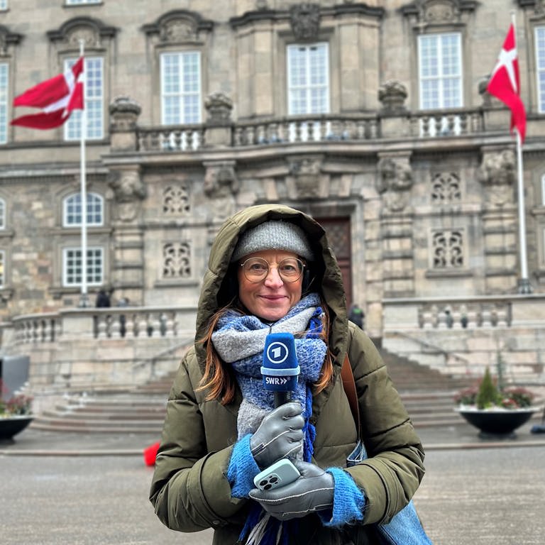 Annelie Malun steht mit Mikrofon in der Hand vor dem Schloss Christiansborg in Kopenhagen. (Foto: SWR)