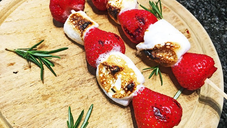 Holzbrett mit Spießen mit gegrillten Erdbeeren und Marshmellows und kleine Zweige Rosmarin dazu (Foto: SWR, Franziska Wonnebauer)