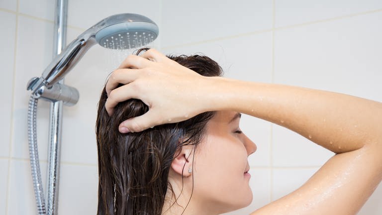 Frau unter der Dusche wäscht sich die Haare unter laufender Brause (Foto: Colourbox)