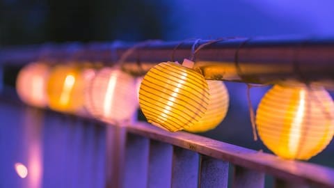 EIne Lichterkette mit Lampions sorgt für eine schöne abendliche Stimmung auf dem Balkon.