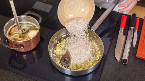 Rezept Graupenrisotto: Graupen werden zu Schalotten und Knoblauch in den Topf gegeben. (Foto: SWR, Corinna Holzer)
