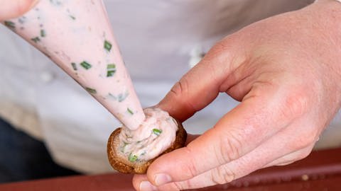 Rezept für gebratene Pilze: Pilzköpfe werden mit Hilfe eines Spritzbeutels mit der Fleisch-Kräuer-Masse befüllt. (Foto: SWR, Corinna Holzer)