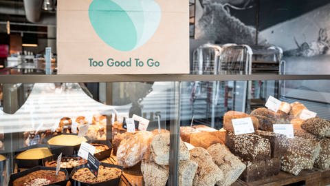Das Logo von "TooGood ToGo" an einer Bäckertheke über Broten (Foto: IMAGO, IMAGO)