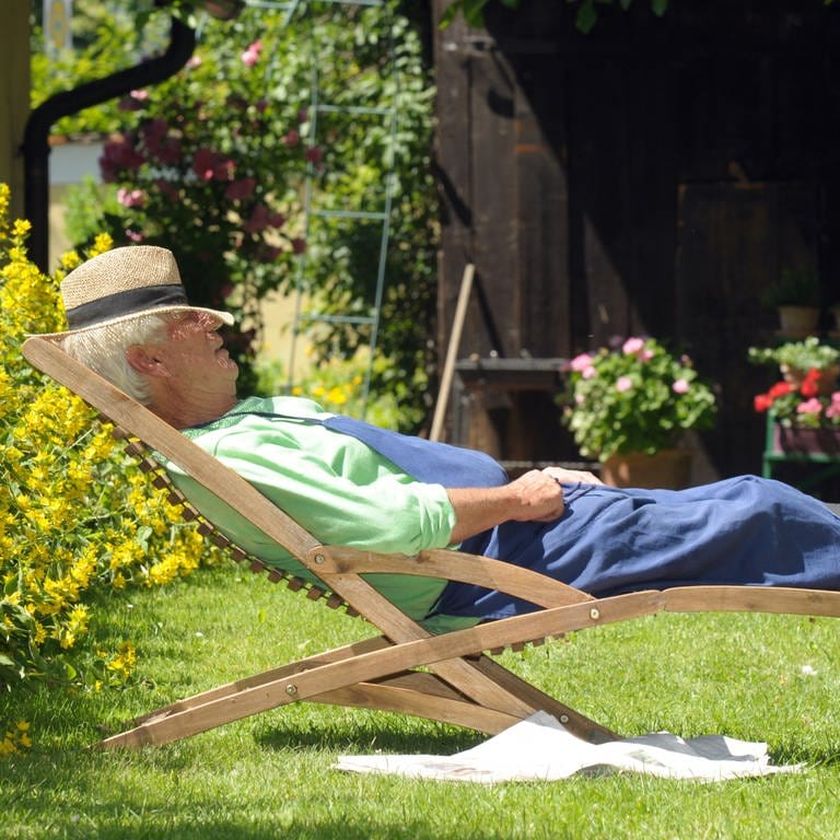 Ein Mann liegt in seinem Garten im Liegestuhl: Mit Pflanzen, die wenig Pflege brauchen, kann es sich der Faule leicht machen. (Foto: picture-alliance / Reportdienste, picture alliance / dpa | Horst Ossinger)