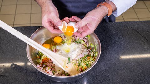 Rezept Lauchkuchen: Joachim Habiger gibt ein Ei in den Topf voller Zutaten hinzu. (Foto: SWR, Corinna Holzer)