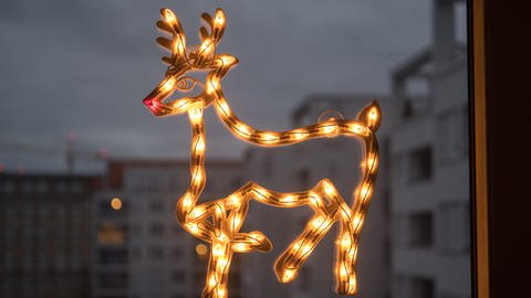 Ein leuchtendes Reh hängt als Weihnachtsdekoration an einem Fenster. (Foto: picture-alliance / Reportdienste, picture alliance / dpa Themendienst | Andrea Warnecke)