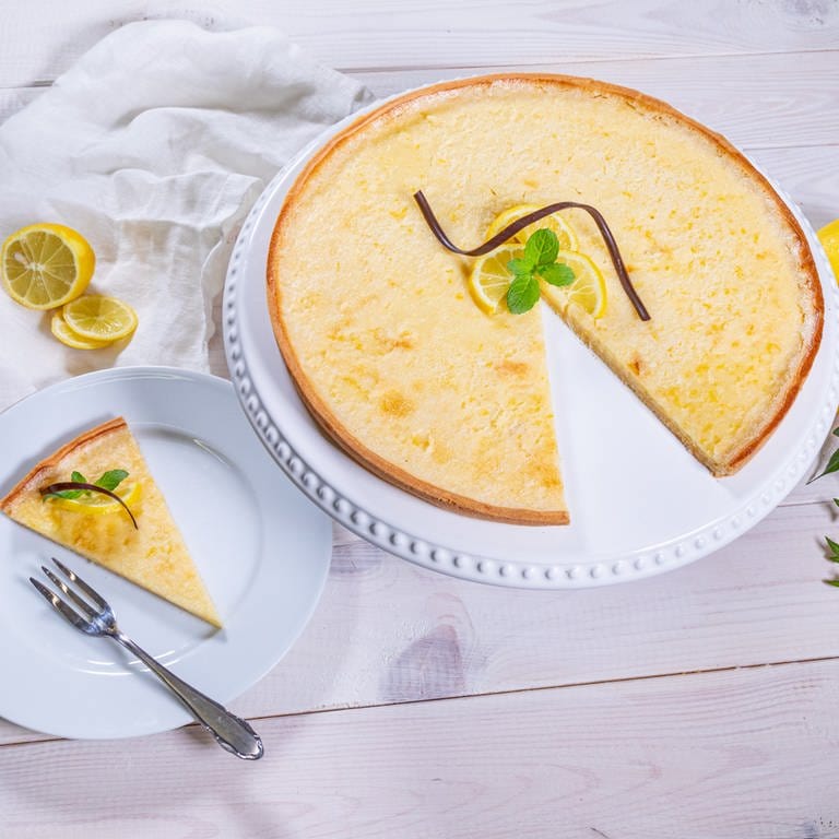 Die fertige Zitronentarte ist angeschnitten und ein Stück von dem Kuchen ist neben der erfrischend und leckeren Tarte auf einem Teller angerichtet. (Foto: SWR, Corinna Holzer)