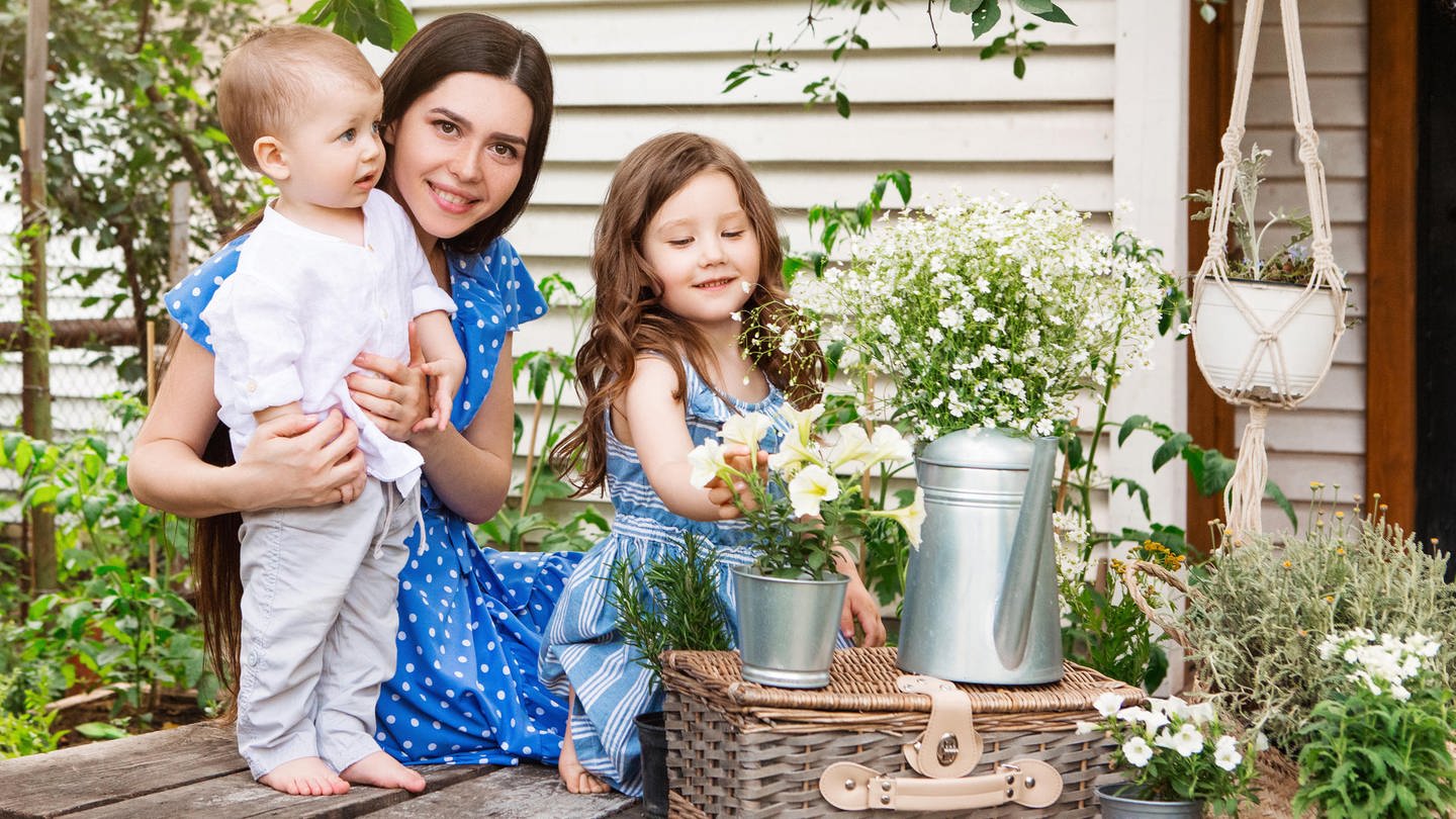 Deko-Trends für Garten, Terrasse und Balkon: Frau mit zwei Kindern in einem Garten beim Dekorieren (Foto: picture-alliance / Reportdienste, Zoonar | Dasha Petrenko)