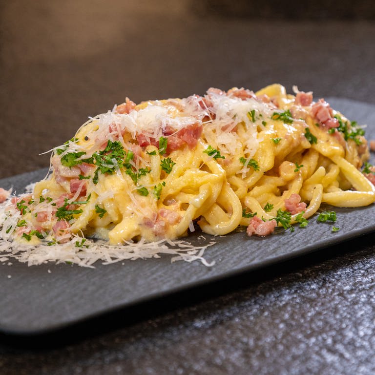 Rezept: Original Spaghetti alla Carbonara angerichtet mit Parmesan auf einer Schieferplatte. (Foto: SWR, Corinna Holzer)