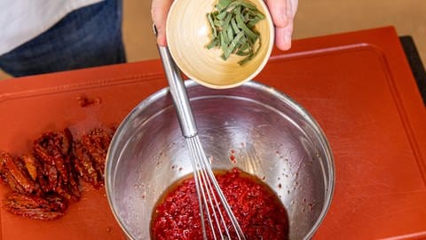 Rezept Kürbisauflauf: Getrocknete Tomaten schneiden und Salbei dazugeben.