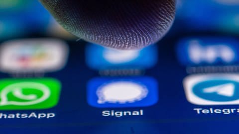 Signal als sicherer Messenger: Ein Finger über einem Handybildschim mit Icons für mehrere Messenger-Dienste (Foto: picture-alliance / Reportdienste, Zacharie Scheurer)
