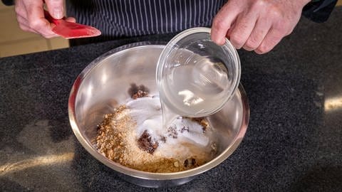 Walnüsse, Brösel, gehackte Rosinen und Zucker werden in eine Rührschüssel gegeben. (Foto: SWR, Corinna Holzer)