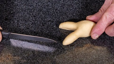 Die Köpfe der Hasen aus Hefeteig mithilfe eines Messers formen. (Foto: SWR, Corinna Holzer)