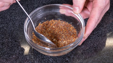 Der Leinsamenschrot für den veganen Kuchen wird in einer Schüssel mit heißem Wasser vermischt. Das Rezept ist einfach.