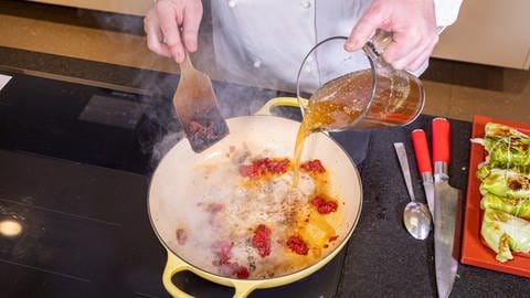 Rezept Kohlrouladen mit Hackfleisch: Der Koch macht mit dem Butterschmalz, Tomatenmark und einer Brühe die Soße in einer Pfanne. (Foto: SWR, Corinna Holzer)