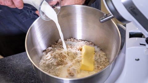 Für den Hefekranz bzw. Hefezopf wird in einer Rühschüssel ein Hefeteig erstellt. Zu Zucker, Butter, Hefe, Salz und Mehl wird Milch hinzugegeben. (Foto: SWR, Corinna Holzer)