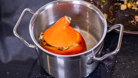 Der vegetarisch gefüllte Kürbis der Sorte Hokkaido wird in einem Topf mit Wasser gekocht. (Foto: SWR, Corinna Holzer)