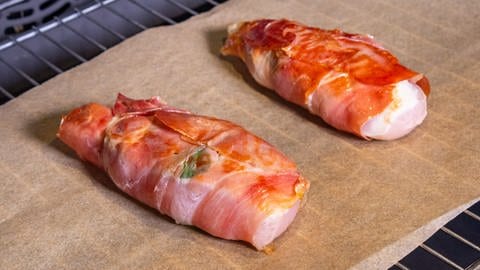 Rezept für Saltimbocca vom Hähnchen: Die mit Schinken umwickelten Hähnchen-Stücke liegen in einem Ofen auf Backpapier und werden gegart. (Foto: SWR, Corinna Holzer)