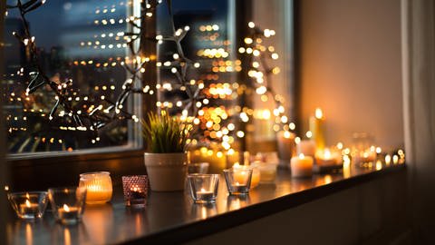 Weihnachtsdeko mit Lichterkette und Kerzen auf der Fensterbank. (Foto: picture-alliance / Reportdienste, picture alliance / Zoonar | Lev Dolgachov)