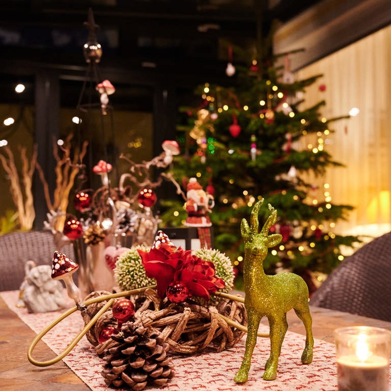 Weihnachtsdeko auf Tisch mit Weihnachtsbaum im Hintergrund.