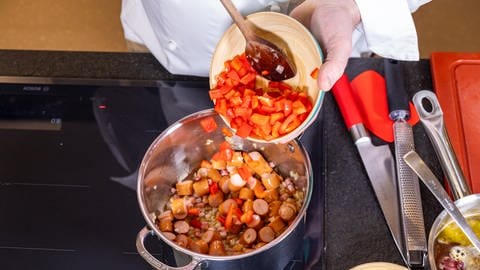 Lecker und unkompliziert an Silvester – Rezept für Würstchengulasch: Roter Paprika wird zu den Würstchen und zu den Zwiebeln hinzugegeben.  (Foto: SWR, Corinna Holzer)