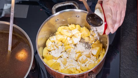 Francine kocht einen deftigen Kartoffeleintopf, auf Schwyzerdütsch: Härdöpfuschnätz. Die Kartoffelstücke werden mit Mehl bestäubt.