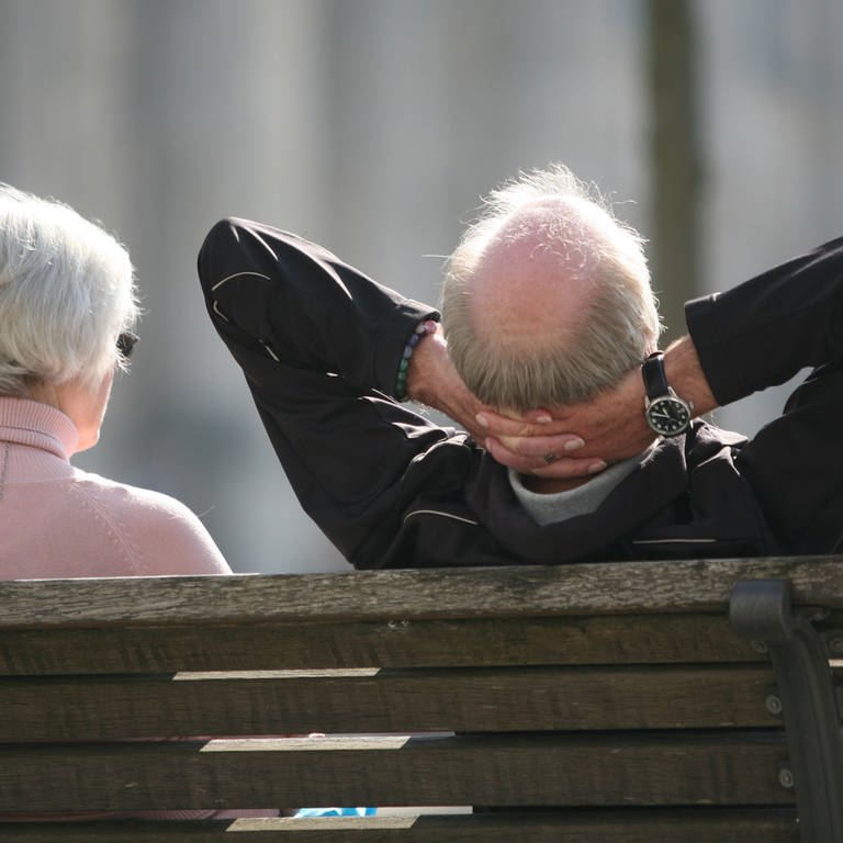Rente und Altersvorsorge - entspannt in den Ruhestand: Ein Rentnerpaar sitzt auf einer Parkbank und ist von hinten zu sehen. Der Mann lehnt sich entspannt zurück und verschränkt die Hände hinter dem Kopf. (Foto: dpa Bildfunk, Picture Alliance)