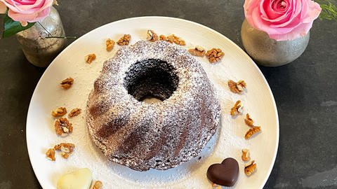 Kuchen in Gugelhupfform auf einem Teller, dekoriert mit Walnüssen