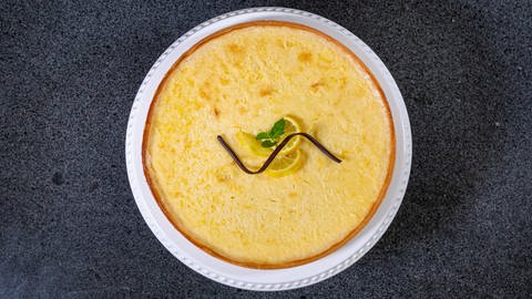 Die Zitronentarte ist frisch gebacken und liegt auf einer Tortenplatte. Die Tarte ist erfrischend und mit Zitronenscheiben lecker dekoriert. (Foto: SWR, Corinna Holzer)