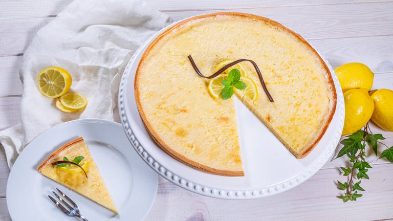 Die fertige Zitronentarte ist angeschnitten und ein Stück von dem Kuchen ist neben der erfrischend und leckeren Tarte auf einem Teller angerichtet. (Foto: SWR, Corinna Holzer)