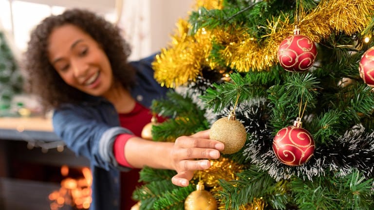 Weihnachtsbaumschmuck basteln und eine Frau schmückt den Christbaum zu Weihnachten.