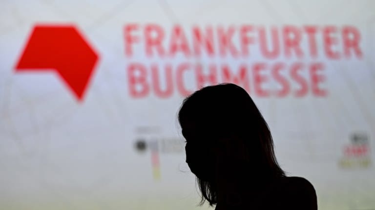 Eine Frau steht am Rande der Eröffnungspressekonferenz der Frankfurter Buchmesse vor einer Projektion (Foto: picture-alliance / Reportdienste, dpa Bildfunk, Arne Dedert)