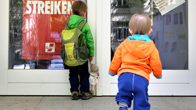 Zwei kleine Kinder stehen vor der Tür eines wegen Streik geschlossenen Kindergartens. (Foto: dpa Bildfunk, picture alliance / Jan Woitas/dpa-Zentralbild/dpa | Jan Woitas)