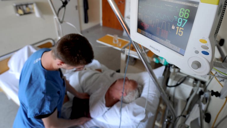 Ein Schlaganfallpatient liegt in einem Bett im Krankenhaus und ein Computerbildschirm zeigt seine vitalen Lebensfunktionen an (Foto: dpa Bildfunk, (c) dpa)