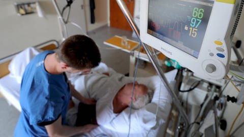 Ein Schlaganfallpatient liegt in einem Bett im Krankenhaus und ein Computerbildschirm zeigt seine vitalen Lebensfunktionen an (Foto: dpa Bildfunk, (c) dpa)