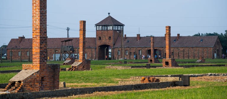 Die Auschwitz-Gedenkstätte heute mit Blick auf das historische Tor und Schornsteine der ehemalige Baracken. (Foto: dpa Bildfunk, picture alliance/Monika Skolimowska/zb/dpa)