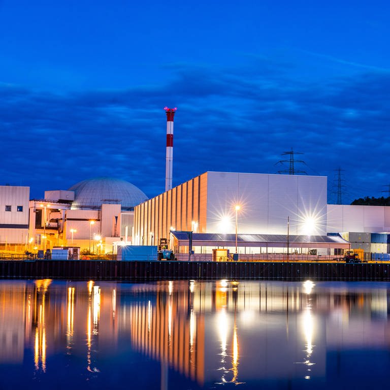 Zur blauen Stunde spiegelt sich das Kernkraftwerk Neckarwestheim im Neckar. Drei Atomkraftwerke sind bundesweit noch am Netz, darunter ist auch Neckarwestheim 2 in Baden-Württemberg. (Foto: dpa Bildfunk, picture alliance/dpa | Christoph Schmidt)