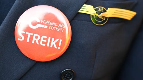 Ein Lufthansa-Pilot trägt bei einer Kundgebung der Pilotengewerkschaft Vereinigung Cockpit einen Button mit der Aufschrift "Streik" auf seiner Uniform. (Foto: dpa Bildfunk, picture alliance/dpa | Uwe Anspach)