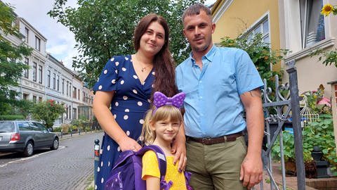 Zusammen mit Mutter Ruslana und deren Partner Andrey freut sich die kleine Viktoria über ihren neuen Schulranzen. (Foto: Caritas Bremen)