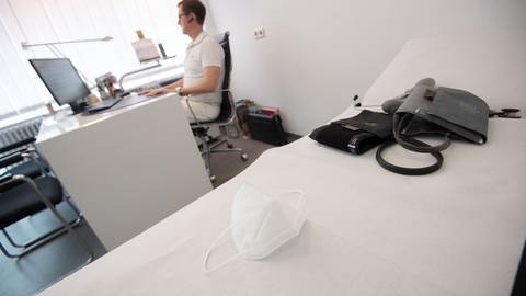 Arzt sitzt in seiner Hausarztpraxis mit einem Telefonhörer am Ohr in einem Behandlungszimmer. (Foto: picture-alliance / Reportdienste, dpa Bildfunk, Marijan Murat)