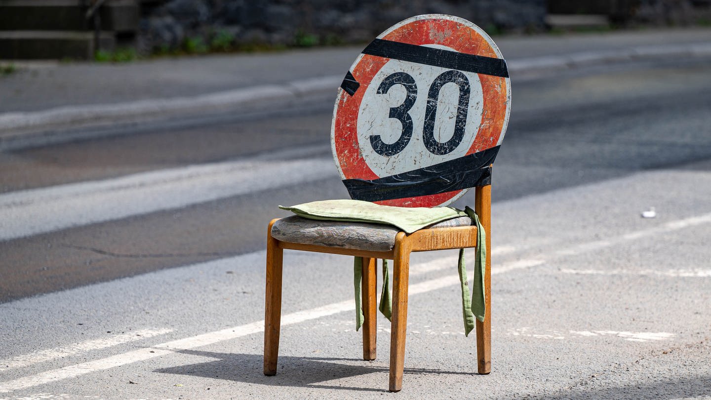 Ein Verkehrsschild das auf eine Tempo-30-Zone hinweist, wurde an einem Stuhl befestigt, der auf der Straße steht. (Foto: picture-alliance / Reportdienste, dpa Bildfunk, Markus Klümper)