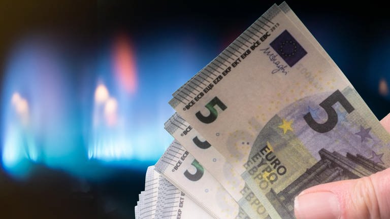 Eine Hand mit Banknoten vor einer Gasflamme. (Foto: picture-alliance / Reportdienste, CHROMORANGE | Andreas Poertner)