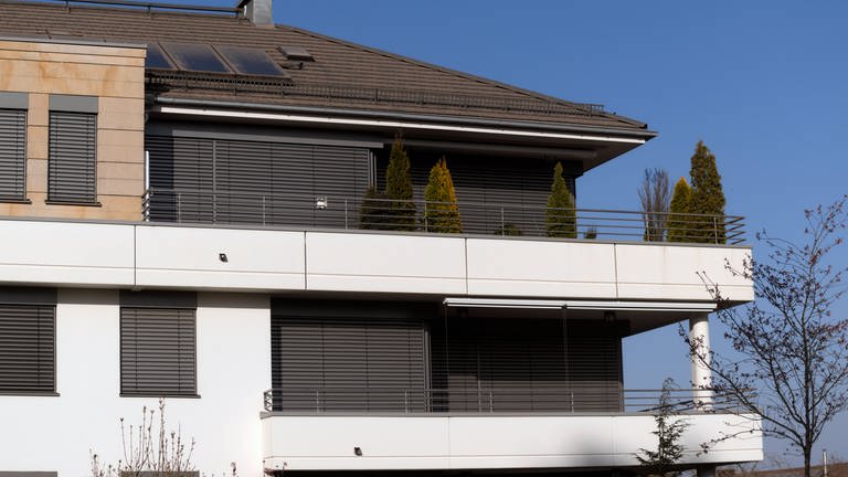 Leer stehende Wohnungen: Die Rolläden auf zwei Stockwerken in einer modernen Wohnanlage sind dauerhaft heruntergelasse. Eine Leerstandssteuer könnte helfen (Foto: IMAGO, IMAGO / MiS)